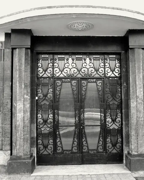 Wrought-iron door under a rounded canopy, Art Deco building